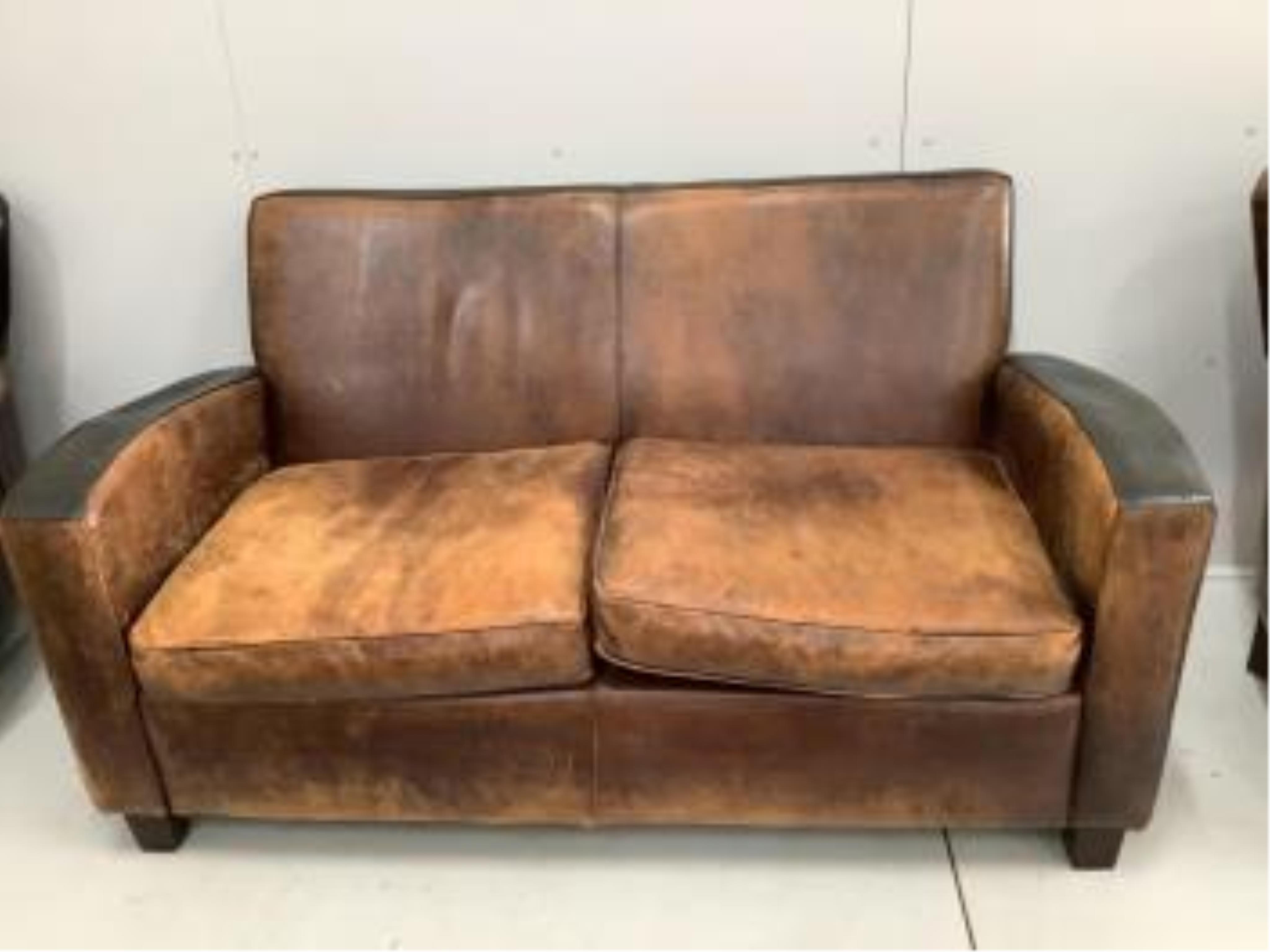 A leather settee, width 156cm, depth 78cm, height 82cm, and a pair of leather wing armchairs. Condition - fair